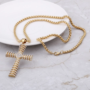 Macro detail of gold-plated hip hop cross pendant with clear crystals on pearl bead chain