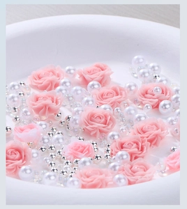 Macro shot of 3D pink resin roses with assorted white pearls and silver beads for nail art