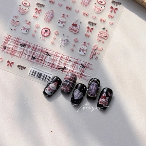 Detail of Christmas nail stickers with snowman, red plaid, and bow patterns on black nails
