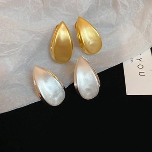 Dettaglio macro di orecchini a goccia spazzolati con placcatura in oro 18k e argento