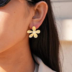 Detailed close-up of golden petal stud earrings with brushed metal texture and zircon centers