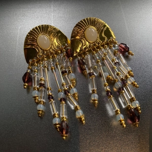 Macro shot of vintage tassel earrings featuring gold texture and purple teardrop beads