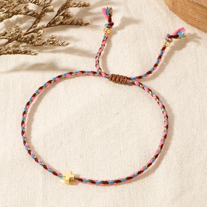 Detailed view of handmade woven cotton bracelet with a small gold cross pendant