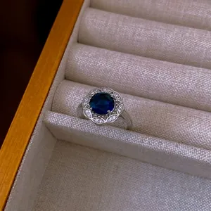 Elegante anello halo con pietra in zircone blu profondo e pavé di cristalli bianchi