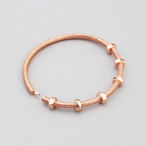 Macro detail of rose gold screw nut bracelet with threaded metal bar and movable hex nuts
