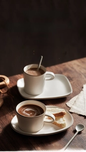 Close-up of matte beige ceramic coffee cup with retro brown rim on dark wood desk