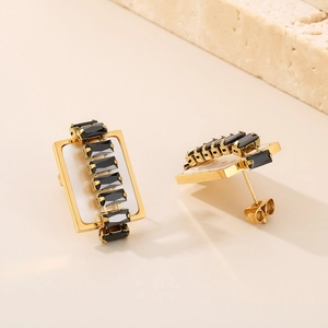 Detail of gold titanium steel earrings with black rectangular gems and shell texture