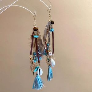 Macro shot of bohemian long tassel earrings with feathers shells and turquoise beads