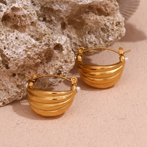 Detail of 18K gold-plated hoop earrings with small pearls on a textured rock base