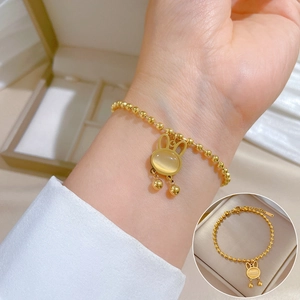 Golden titanium steel beaded bracelet with cute cat-eye rabbit charm on female wrist