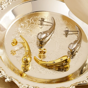 Elegant gold and silver teardrop earrings with crystals displayed on a silver tray