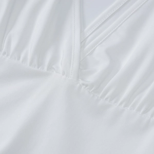 Detail of the plunging V-neckline and elegant ruched pleats on the white dress fabric