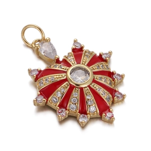 Detail of a gold sunburst pendant with red enamel and sparkling cubic zirconia stones