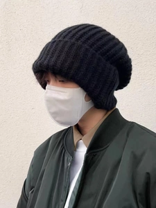 Detail of chunky black knit beanie styled with a green jacket and mask for winter look