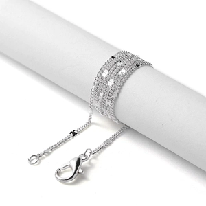 Macro shot of silver metal jewelry chain with lobster clasp on a white display stand