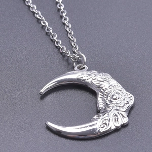 Macro shot of silver crescent moon pendant featuring intricate rose floral relief