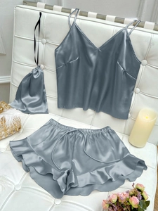 Detailed view of silver satin camisole set with ruffled shorts and drawstring storage bag