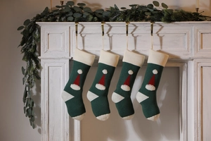 Detail of four knitted dark green Christmas stockings with 3D Santa hat patterns