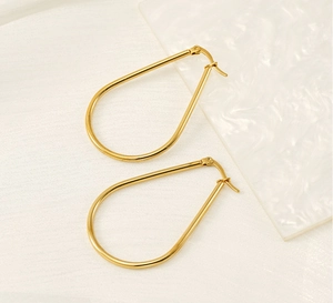 Close-up of golden teardrop hoop earrings featuring a polished mirror finish and hinge closure