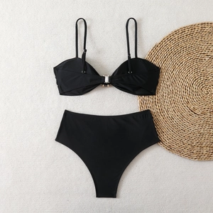Detail of black bikini top with crystal rhinestone buckle on textured background