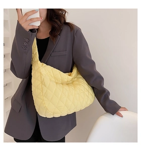 Detailed close-up of a large yellow quilted nylon dumpling bag worn over the shoulder