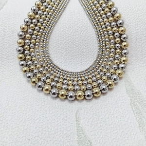 Detail of layered gold and silver stainless steel beaded necklace with gradient bead sizes