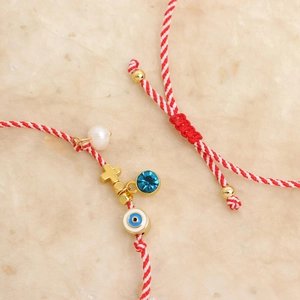 Detailed macro shot of a hand-woven bracelet with evil eye, cross and pearl charms
