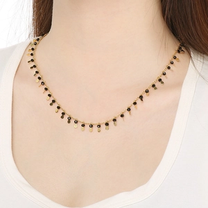 Detail of gold necklace featuring alternating black crystal beads and golden teardrop charms