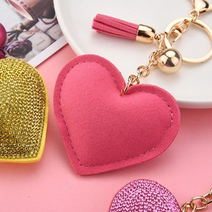 Macro detail of pink suede heart keychain with sparkling rhinestones and matching tassel