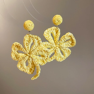 Macro shot of bright yellow raffia woven flower earrings with detailed handmade texture