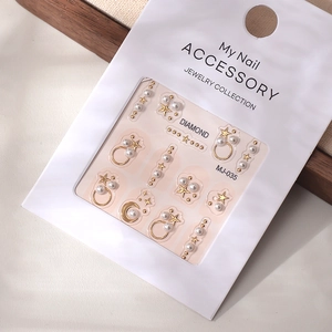Detail of star and moon nail charms with pearls and gold accents on packaging card