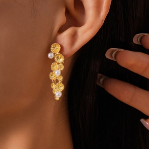 Detail view of gold flower earrings with elegant tassels and white pearl accents