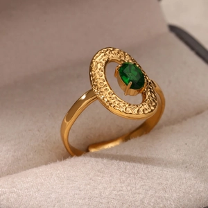 Dettaglio macro di un anello vintage dorato martellato con incastonata una gemma verde ovale