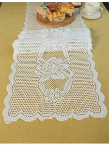 Detailed view of white floral lace table runner with elegant scalloped edges on a table