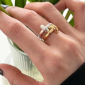 Detailed view of bicolor intertwined silver and gold knot ring on model finger