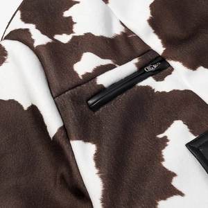 Detail of cow print faux fur jacket with leather-trimmed zipper pocket and soft texture