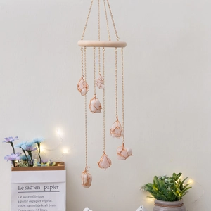 Detail of wooden wind chime with seven raw pink crystal stones on gold metal chains