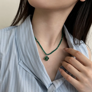 Close-up of S925 silver clover necklace with green crystal beads on a model