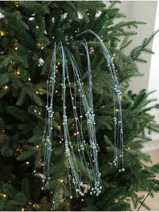 Gros plan d'une branche perlée bleu clair et argentée sur un sapin de Noël illuminé