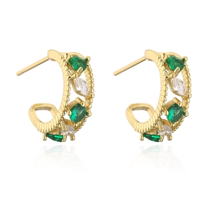 Macro shot of gold-plated C-shaped earrings with inlaid green and white cubic zirconia