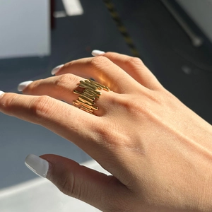Detail of irregular gold lava ring with high-shine metallic texture on model finger