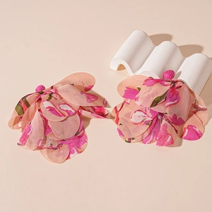 Detailed view of pink floral fabric earrings with layered petals on stone props