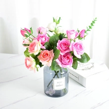 Artificial silk roses in pink and champagne colors inside a grey glass vase for home decor