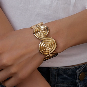 Detailed view of women's gold spiral geometric cuff bracelet with a polished metal texture
