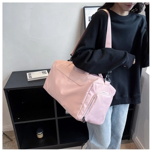 Pink waterproof sports gym bag shown on shoulder for size and scale comparison