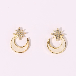 Star and moon earrings in gold finish with sparkling white crystals on pink background