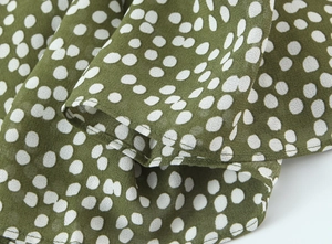 Vue macro du tissu à pois vert olive montrant les coutures et la texture textile