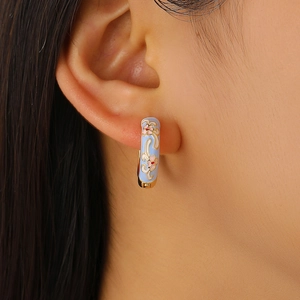 Close-up of vintage light blue enamel hoop earrings with pink flower and gold detailing