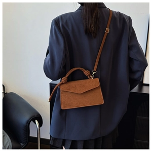 Detail of caramel matte leather handbag featuring a unique knotted handle and adjustable strap