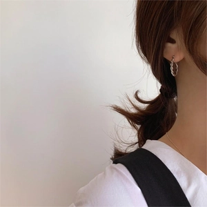 Detail of twisted 925 silver hoop earrings on model with high polish finish